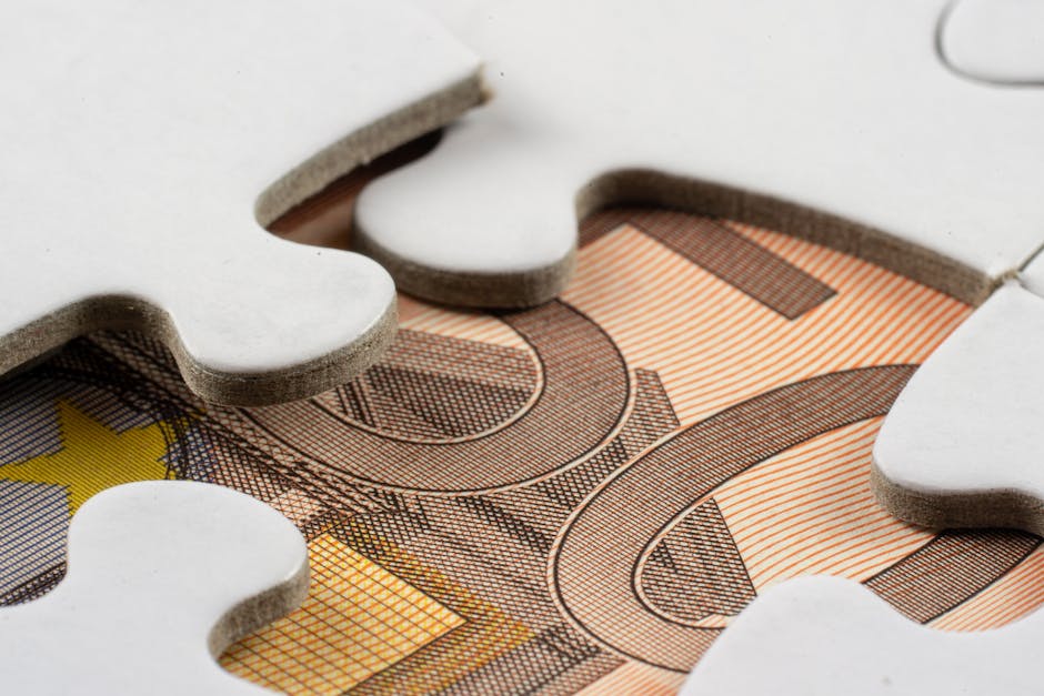 Detailed macro view of white puzzle pieces partially covering a Euro banknote.