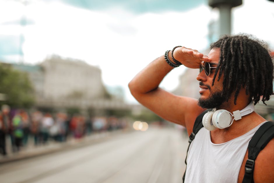 Stylish young man with sunglasses and headphones, enjoying a sunny day outdoors in the city.