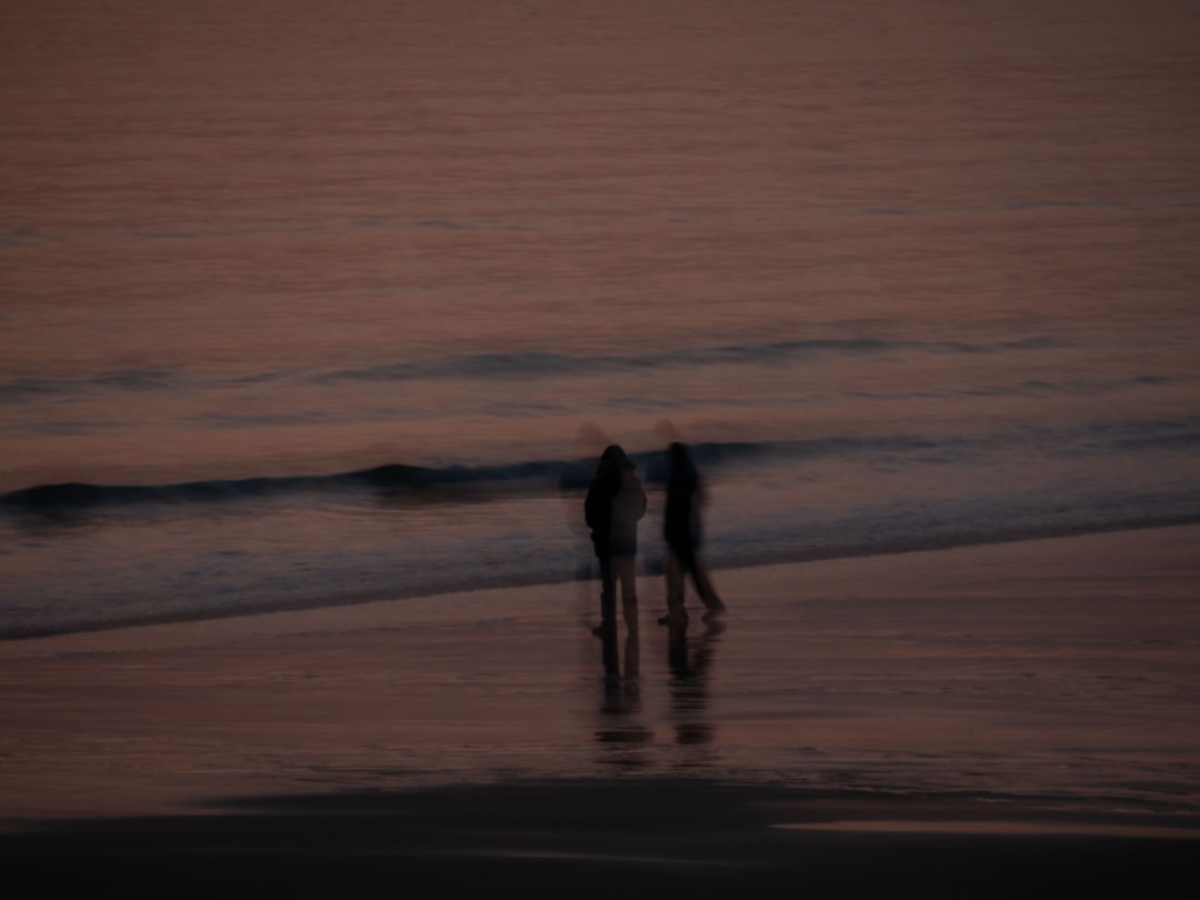 a couple of people standing on top of a beach