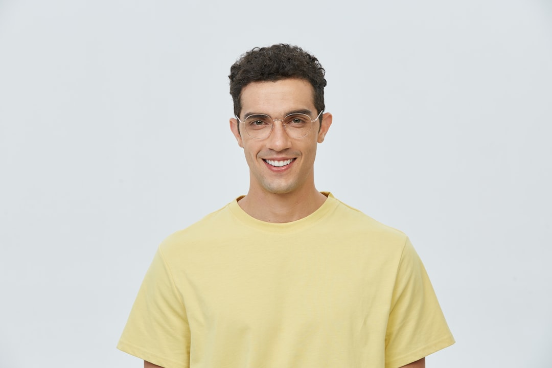 A man in a yellow t - shirt smiles at the camera