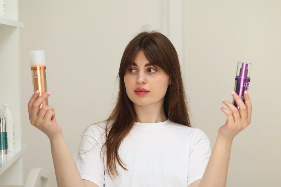 A young woman compares two cosmetic products while standing indoors, unsure of which to choose.