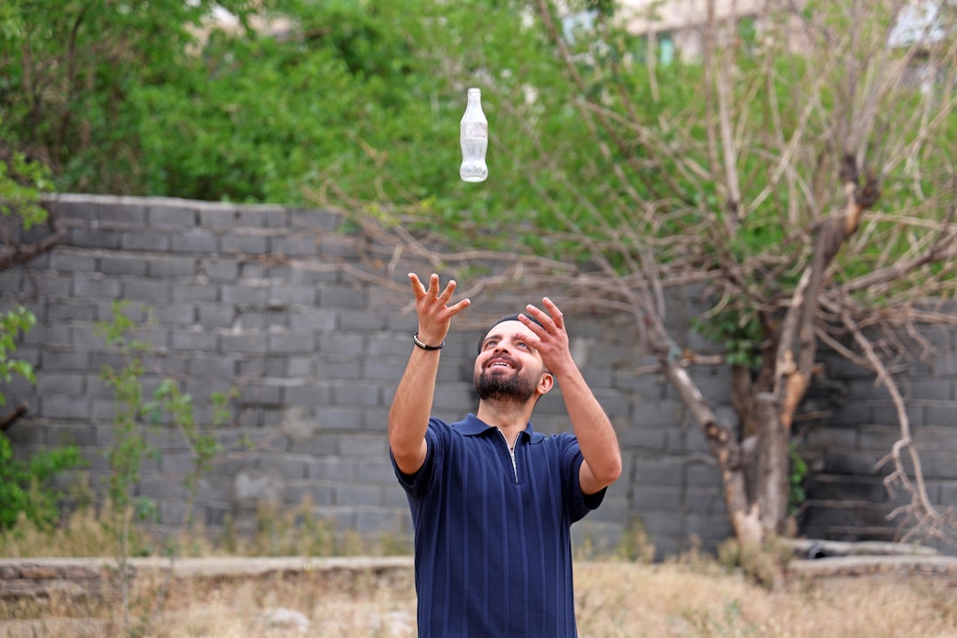 Man juggling a white bottle outdoors