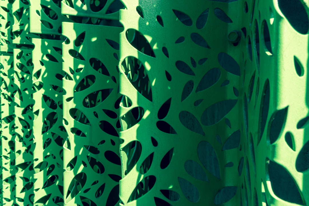 a close up of a metal fence with leaves on it