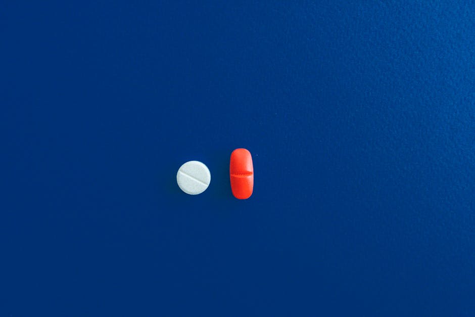 Simple flat lay of two pills on a blue background, perfect for healthcare themes.