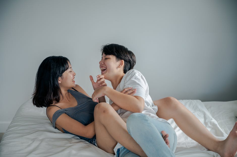 Two women sharing a joyful and intimate moment on a bed indoors.