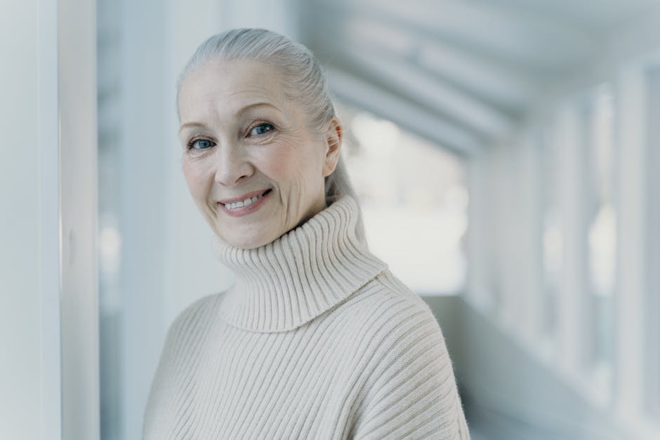 Elegant senior woman with grey hair smiling in a serene indoor setting.
