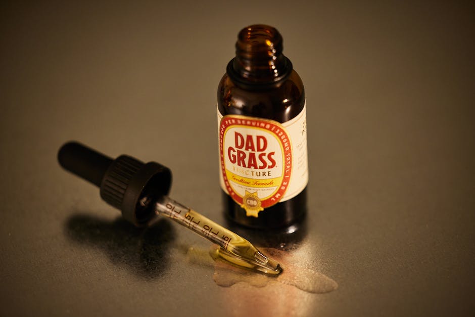 An open CBD tincture bottle with a dropper on a reflective surface.
