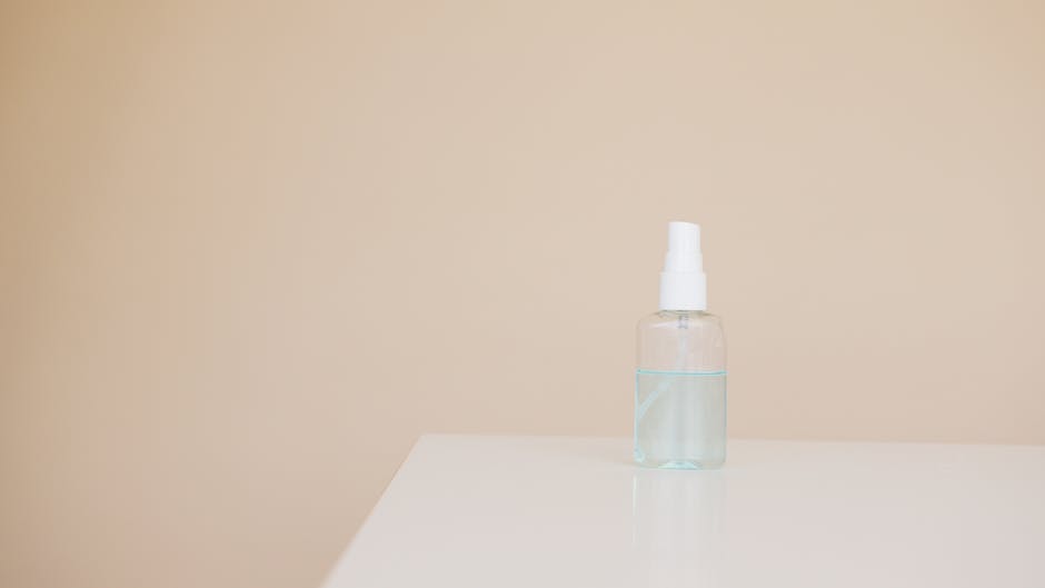 Small plastic bottle of hand antiseptic on white table near light brown wall
