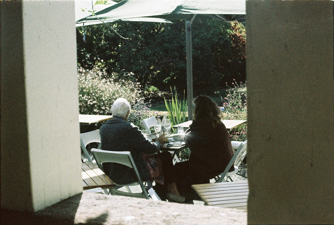 A couple of people sitting at a table under an umbrella