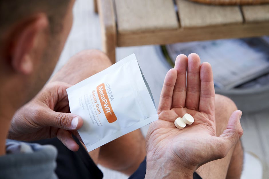 Close-up of a man holding pills and a package indoors.