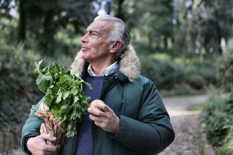 Senior man holding fresh produce and apple, enjoying nature walk.