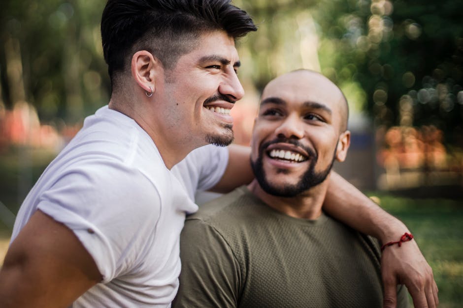 An affectionate interracial gay couple enjoying a moment outdoors in a park.