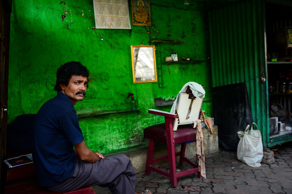 Man seated indoors with a vibrant green rustic background, providing an authentic local vibe.