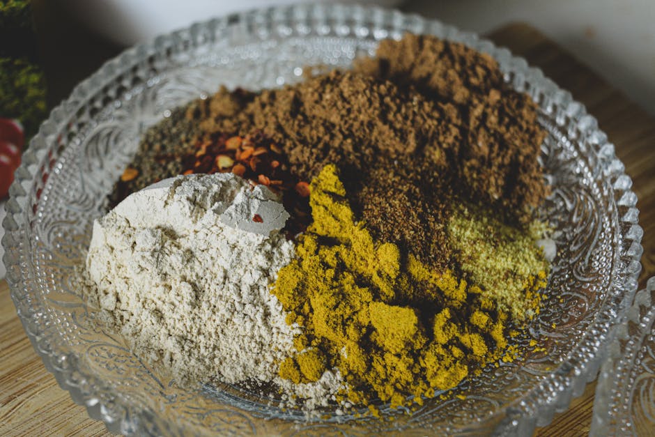 A close-up shot of various spices and powders in a decorative glass bowl.