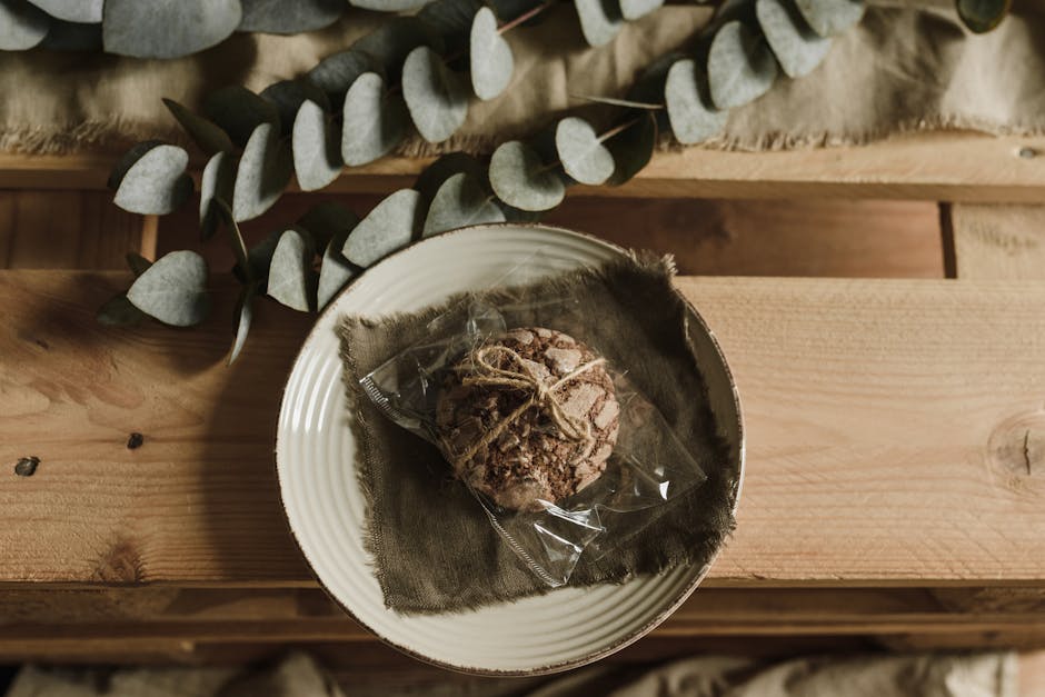 A rustic-style cookie wrapped with twine on a plate, accented by eucalyptus leaves.