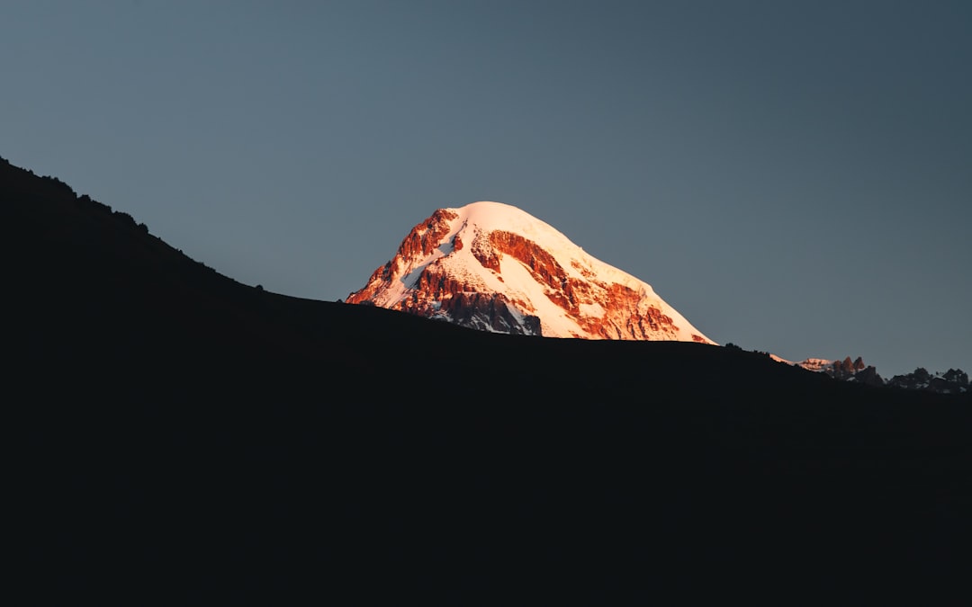 Snow-capped mountain peak illuminated by golden hour light.
