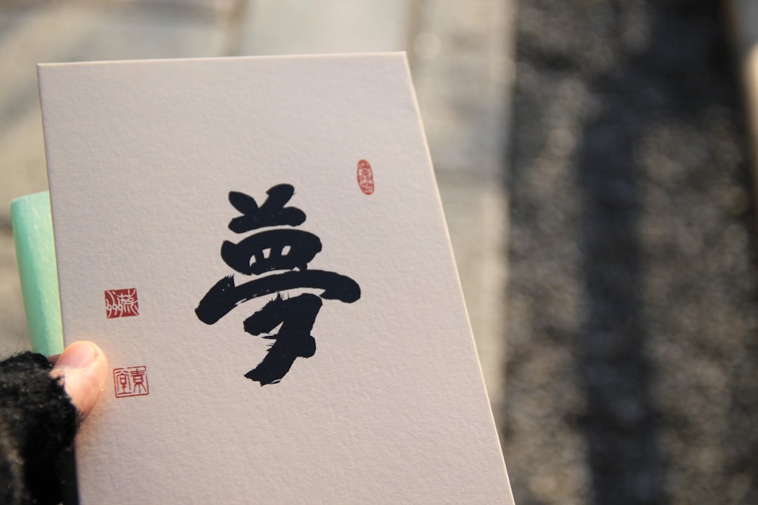 a person holding up a piece of paper with chinese writing on it