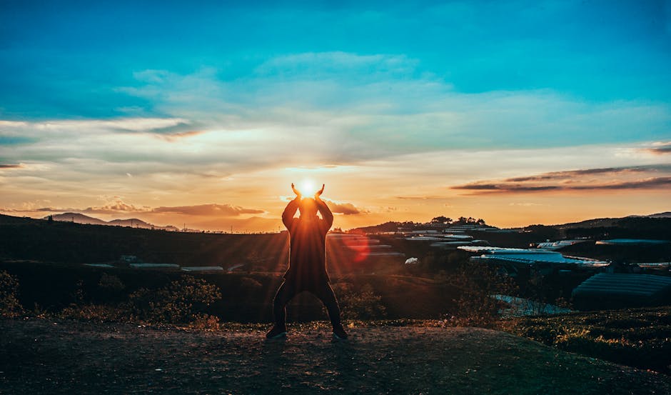 A person silhouetted against the sunrise in a picturesque landscape, capturing the beauty of dawn.