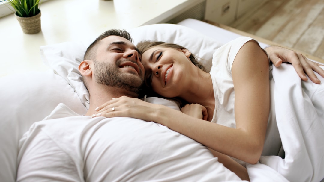Couple cuddling in bed with eyes closed
