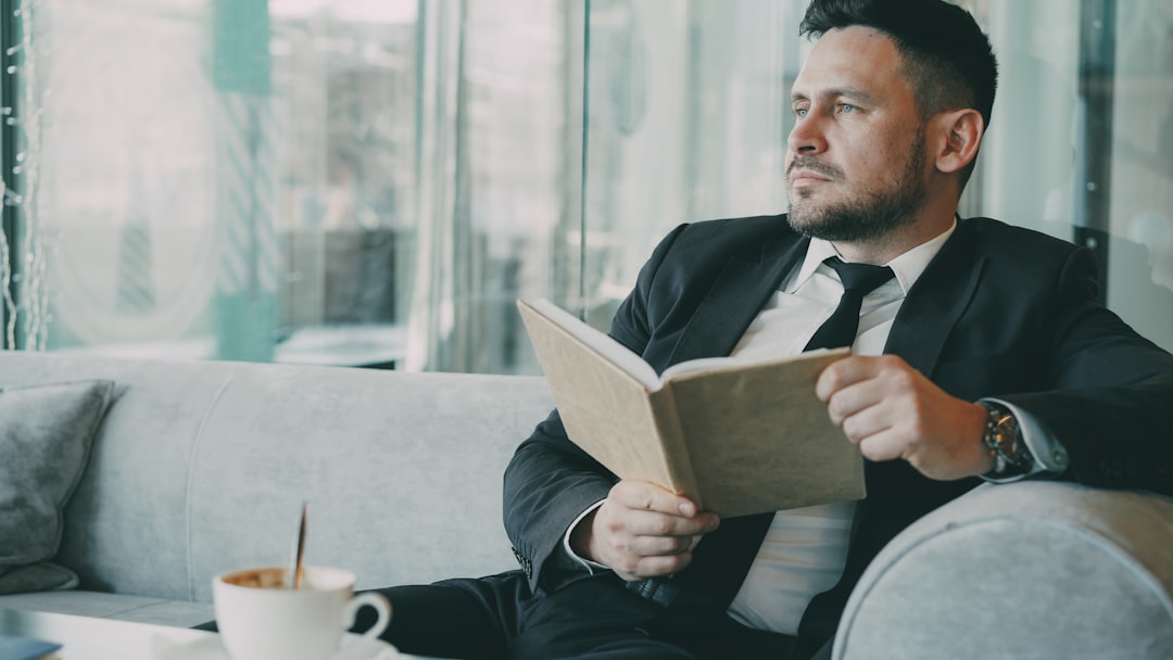 Man in suit reading a book with coffee.