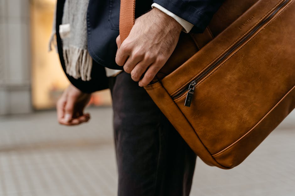 A fashionable man carrying a brown leather bag hints at modern business travel.