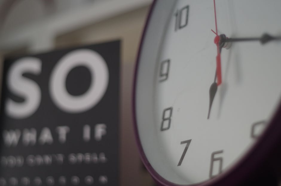 An analog wall clock showing time with a motivational sign partially visible in the background.
