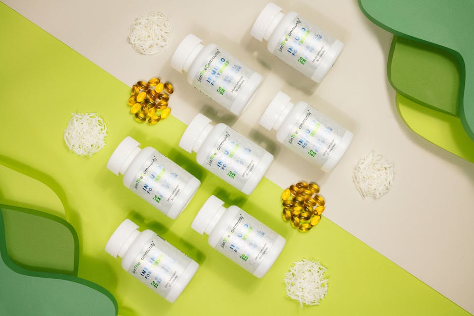 Flat lay of vitamin bottles with capsules and decorative elements against a green and white backdrop.