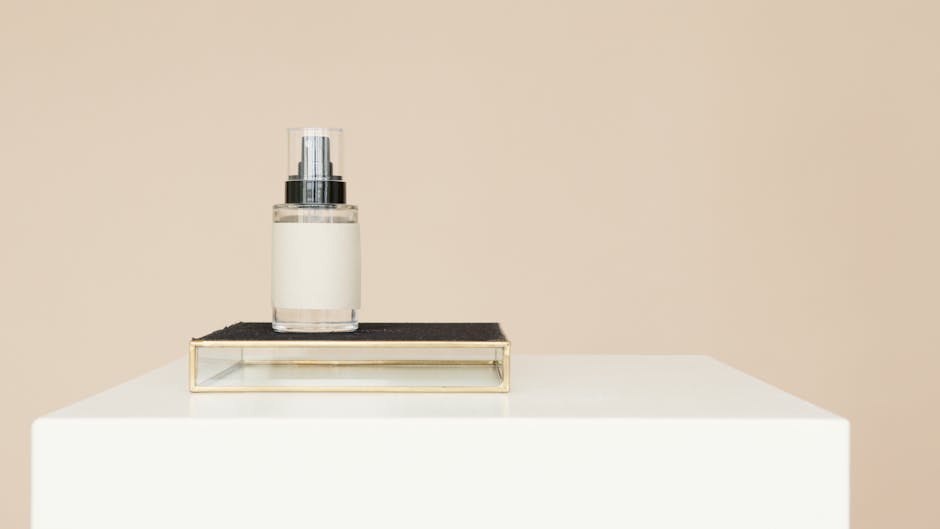 Elegant still life of a glass spray bottle on a white table against a beige background.